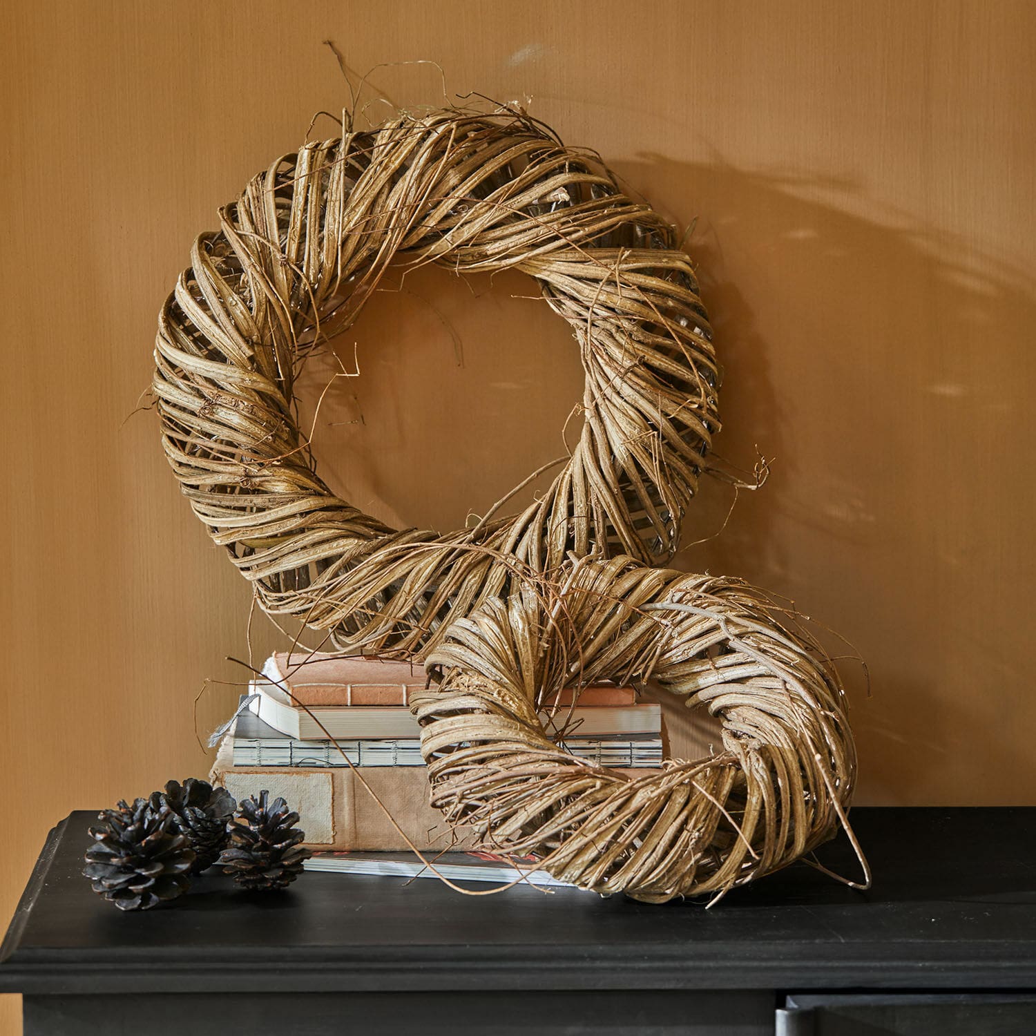 Krans set van 2 Lunéor Decoratieve kransen van natuurlijk beige wilgenmateriaal op een zwarte tafel met boeken