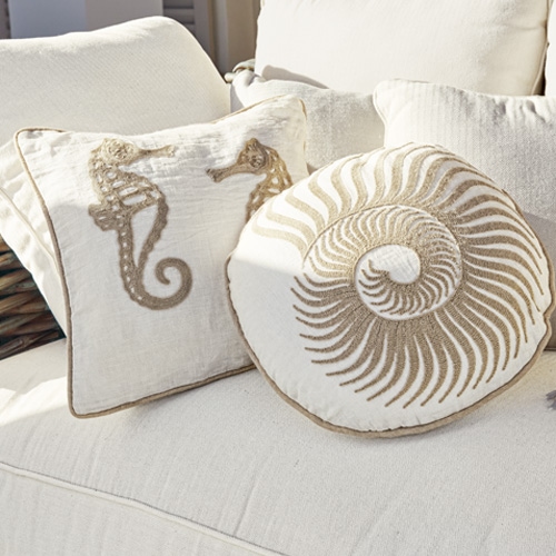 Decoratieve katoenen kussens in crème met zeepaardje- en schelpmotief op lichte bank