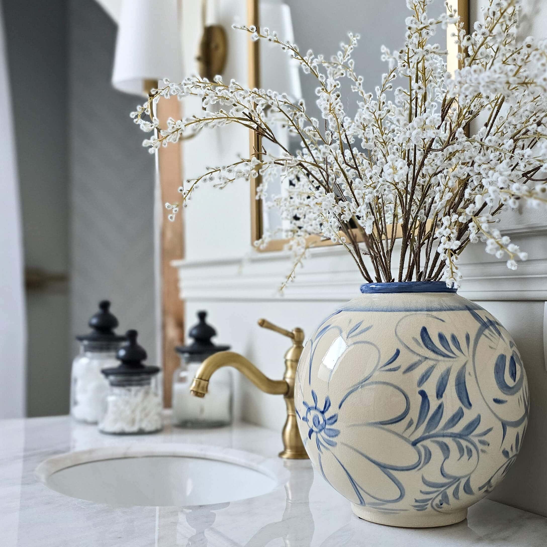 Ronde keramische vaas met blauw bloemmotief op marmeren badkamerblad met decoratie