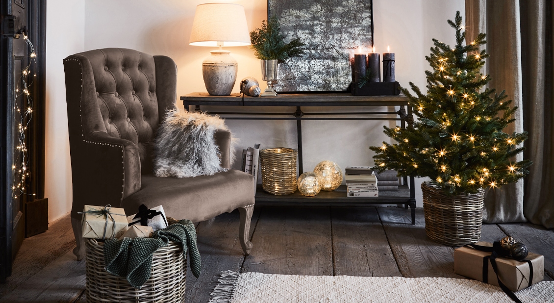 Gezellige woonkamer met bruine fluwelen stoel, versierde kerstboom en decoraties op houten vloer