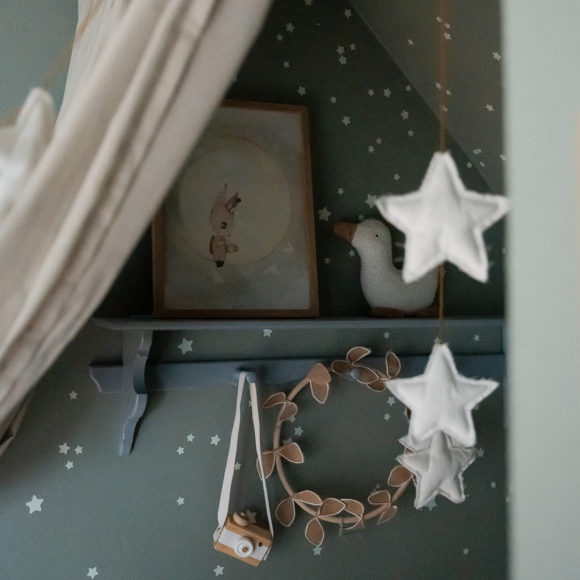 Kinderwanddecoratie met sterren, pluche eend en houten camera op groene achtergrond