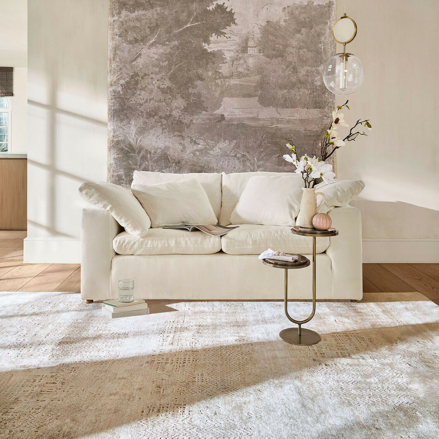 Bank Everholt Beige bank met zachte kussens voor muur met decoratieve muurschildering en bijzettafel met bloemen