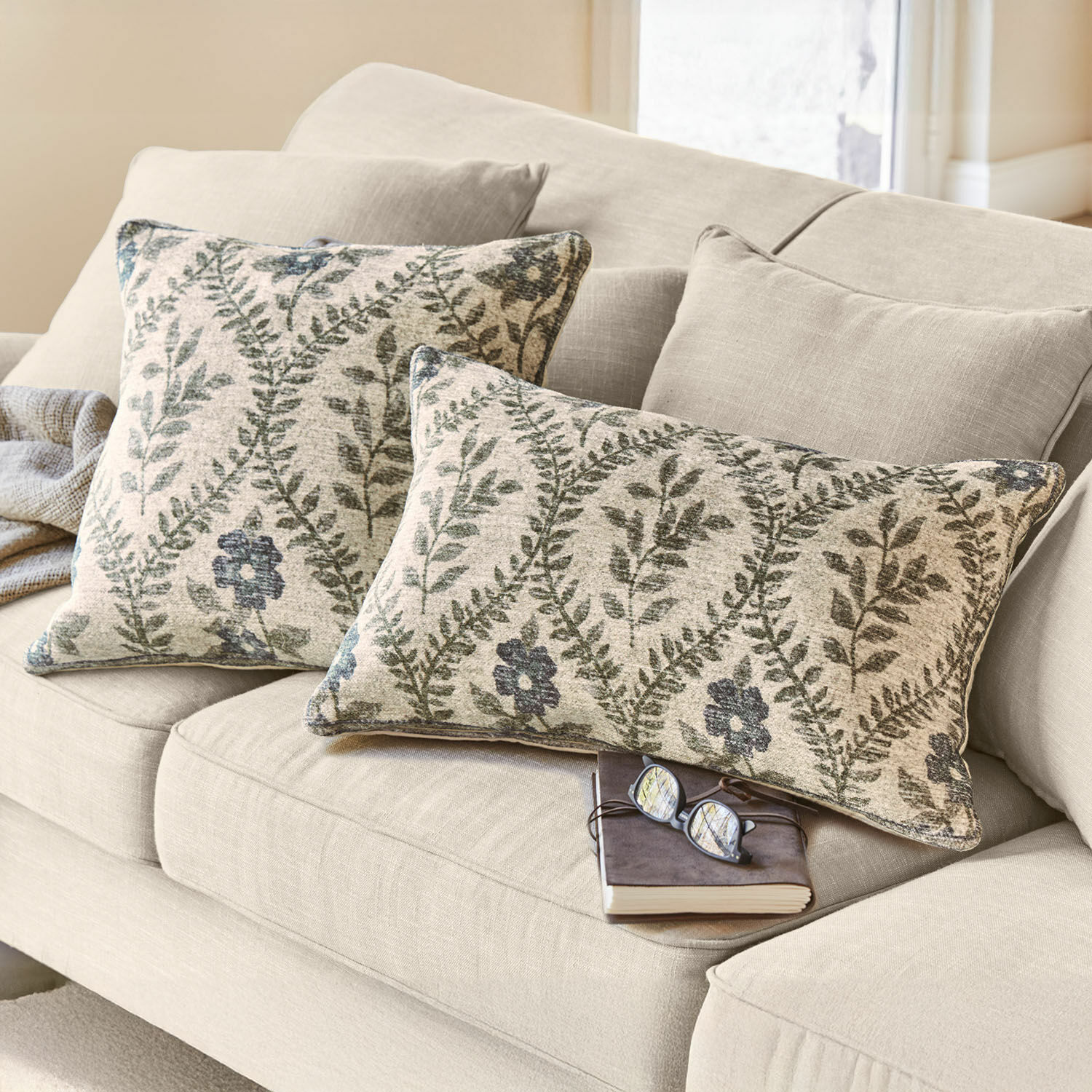 Kussenhoes set van 2 Vellouris Beige bank met twee decoratieve kussens met groen blad- en bloemenpatroon, zachte stof