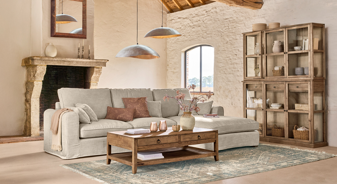 Gezellige woonkamer met beige bank, houten salontafel en rustieke vitrinekast van natuurlijke materialen