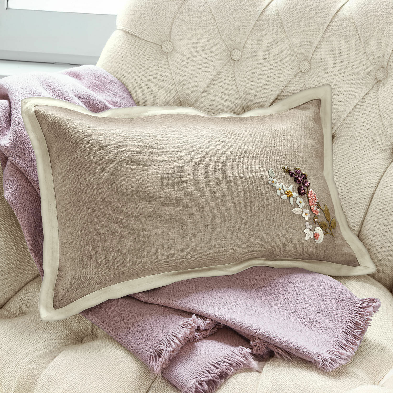 Kussenhoes Tavaline Beige linnen kussen met bloemenborduursel op lichtroze deken op stoel, interieurdecoratie