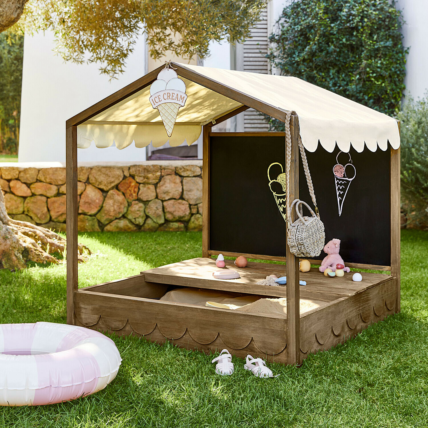 Zandbak Pavillonet Houten zandbak met beige doekdak en krijtbord, speelgoed en ijsdecoraties in de tuin