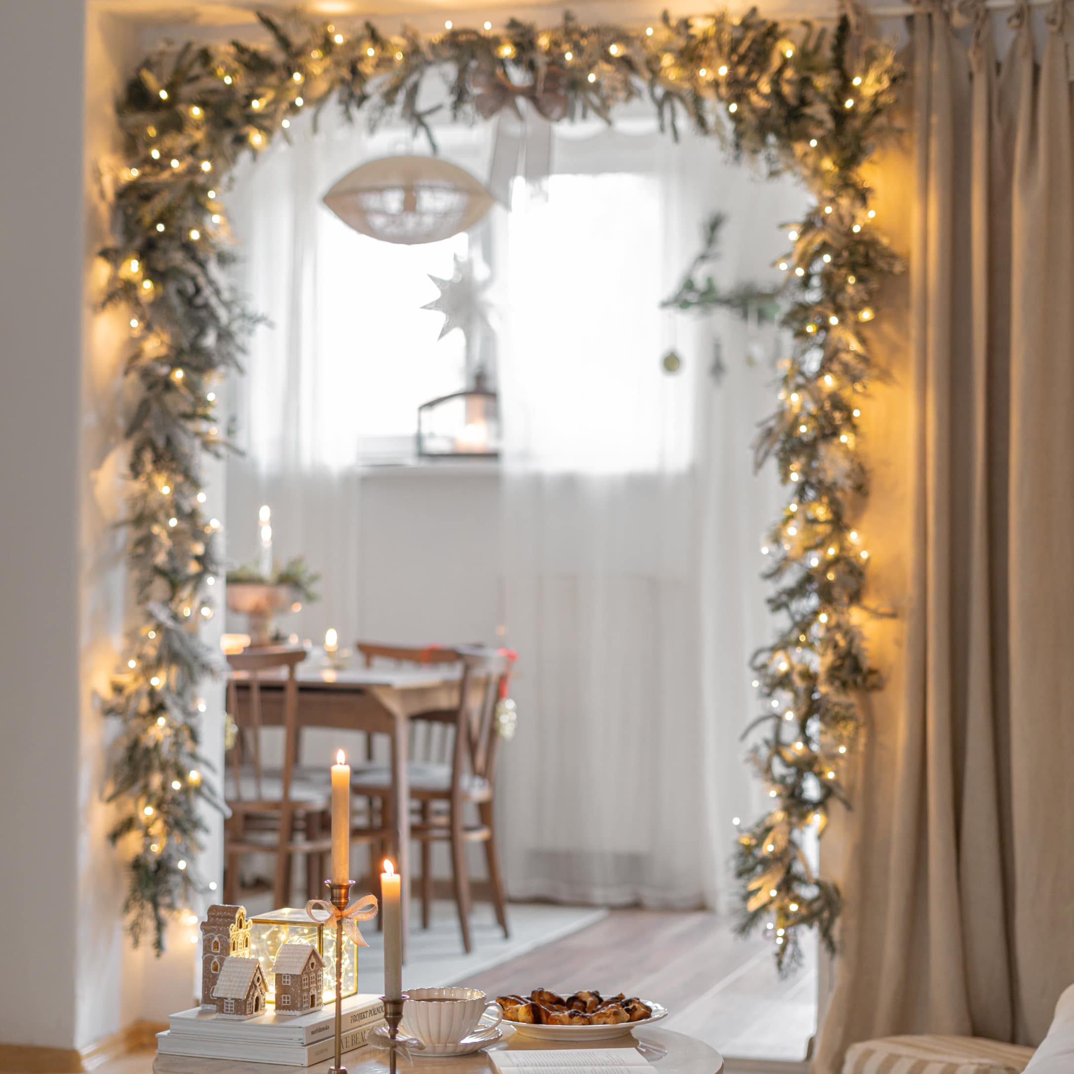 Kerstdecoratie met lichtslinger en kaarsen in gezellige ruimte met houten tafel