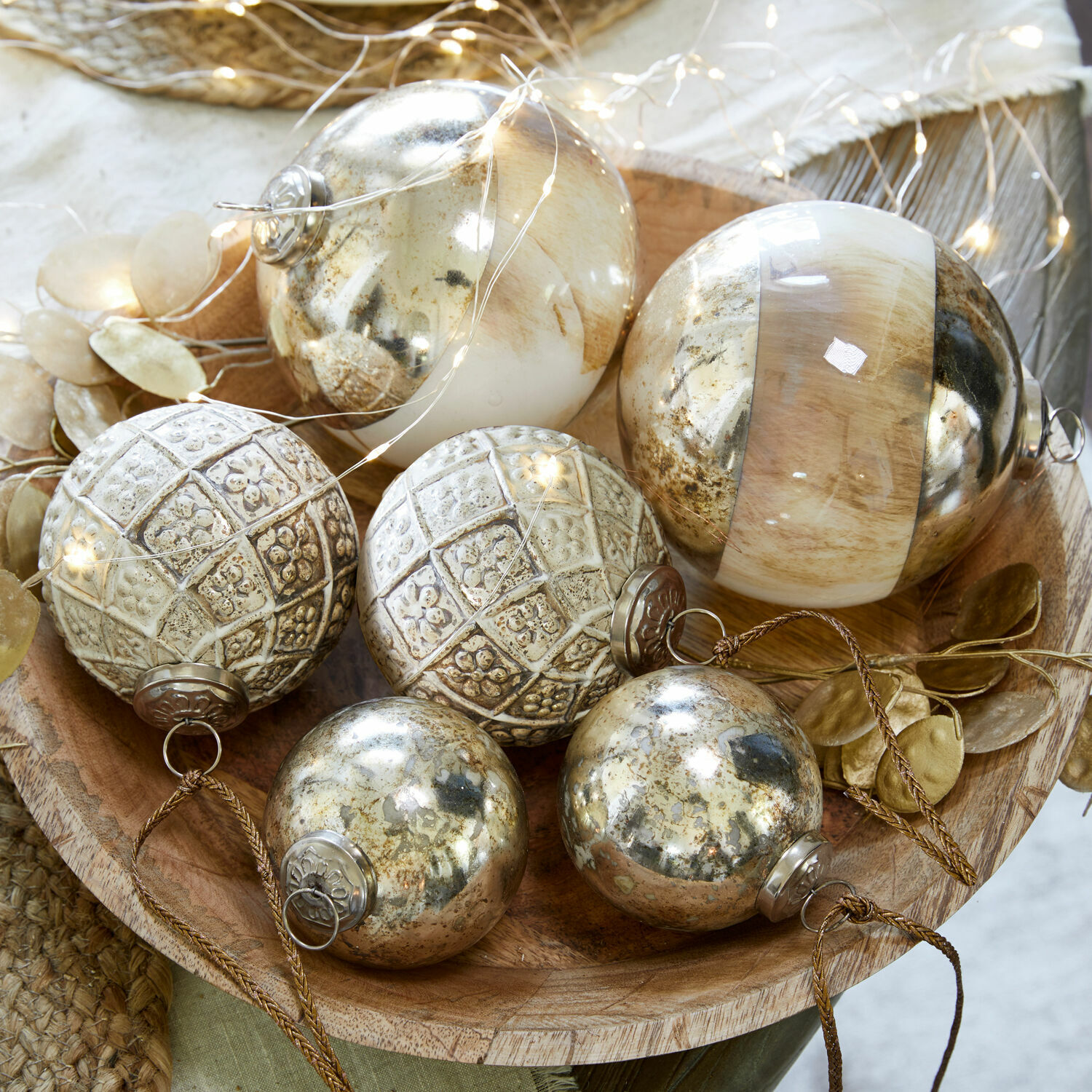 Decoratieve kerstballen in goud- en beige tinten in een houten schaal, feestelijke versiering