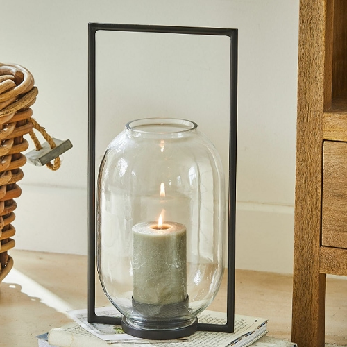 Glazen lantaarn met zwart metalen frame en groene kaars voor interieurdecoratie