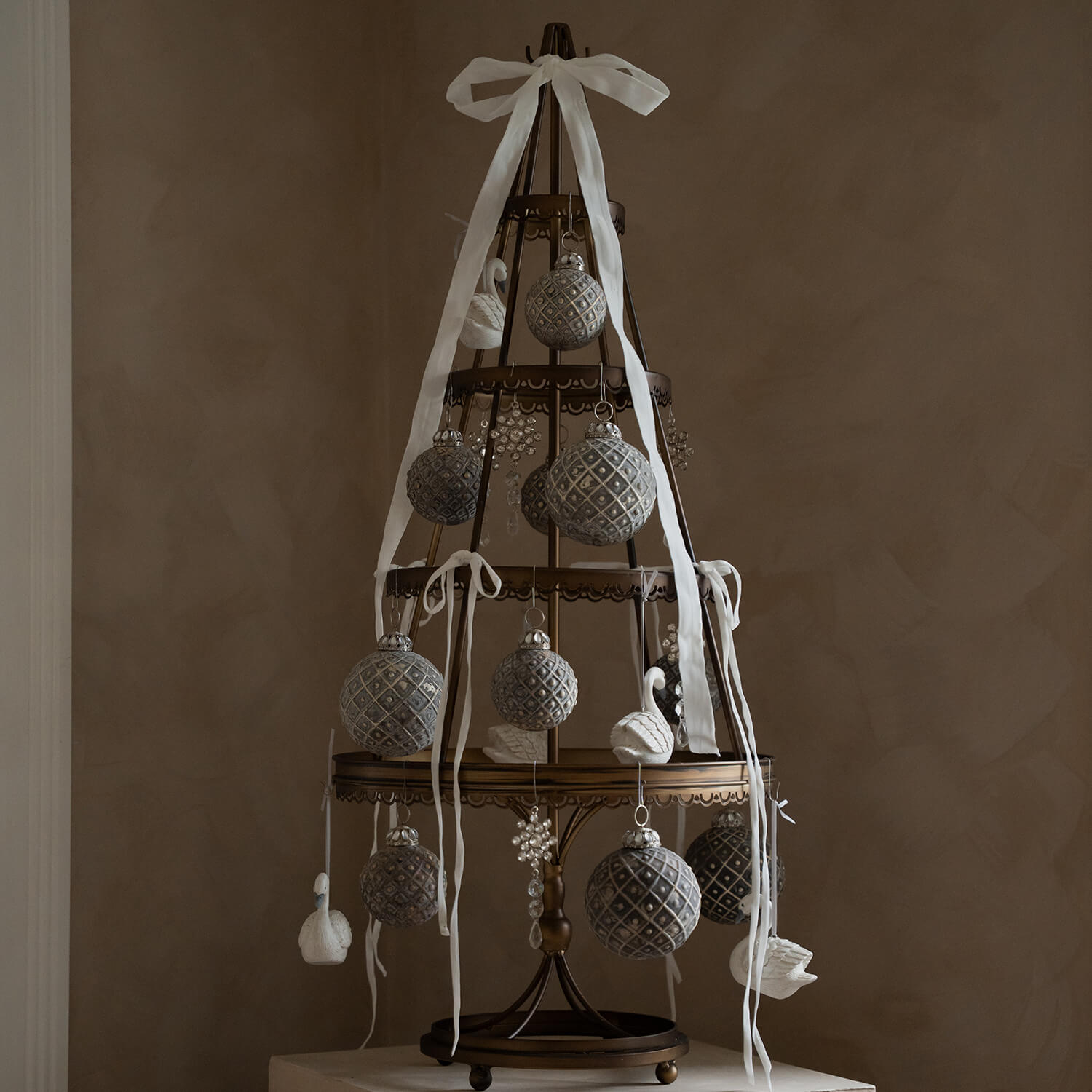 Decoratieve metalen kerstboom met grijze ballen en witte linten in vintage stijl
