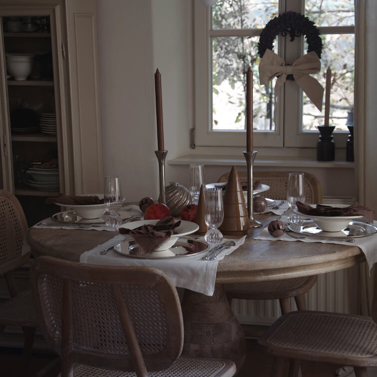Rustieke houten tafel met kerstdecoratie en bruine kaarsen in een gezellige eetkamer