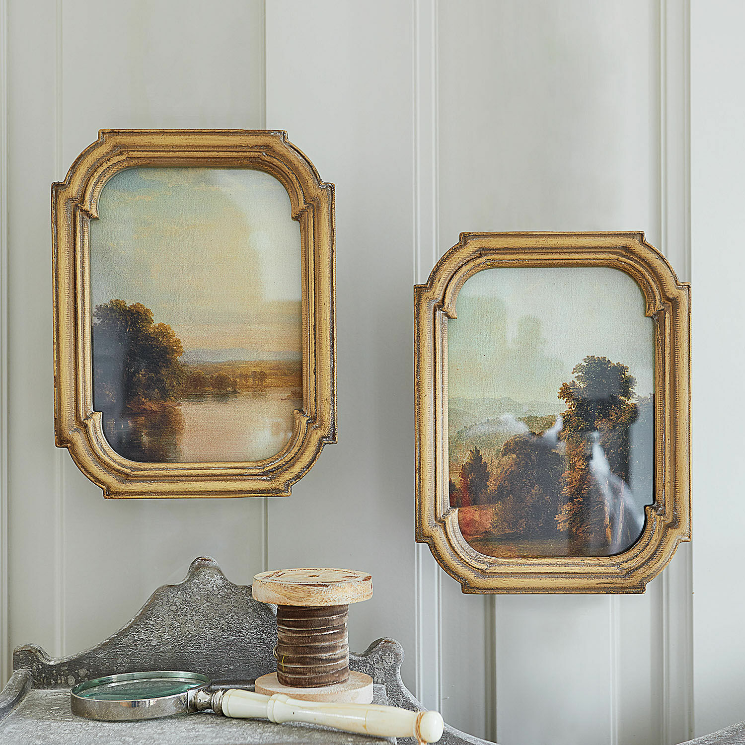 Schilderij set van 2 Fleuroix Twee landschapschilderijen in gouden houten lijsten aan lichte muur, vintage interieurdecoratie