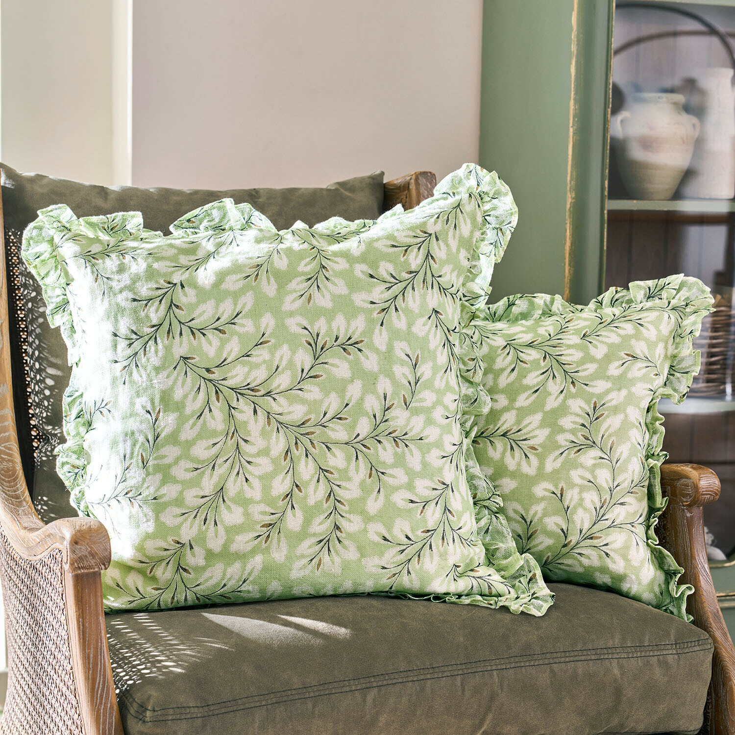 Groene sierkussens met wit bladmotief en ruches op groene stoel, woontextiel