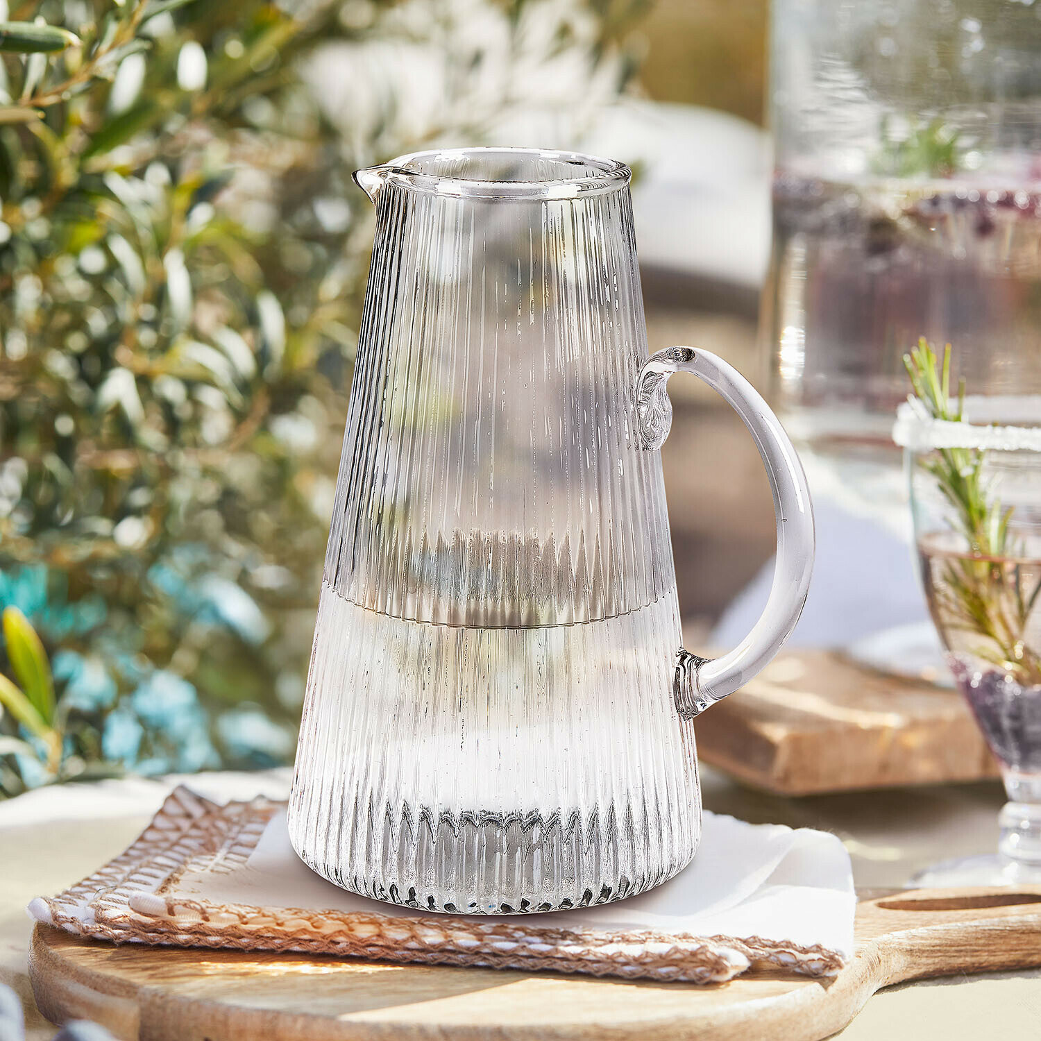Transparante glazen kan met geribbeld patroon en handvat voor zomerse dranken op tafel