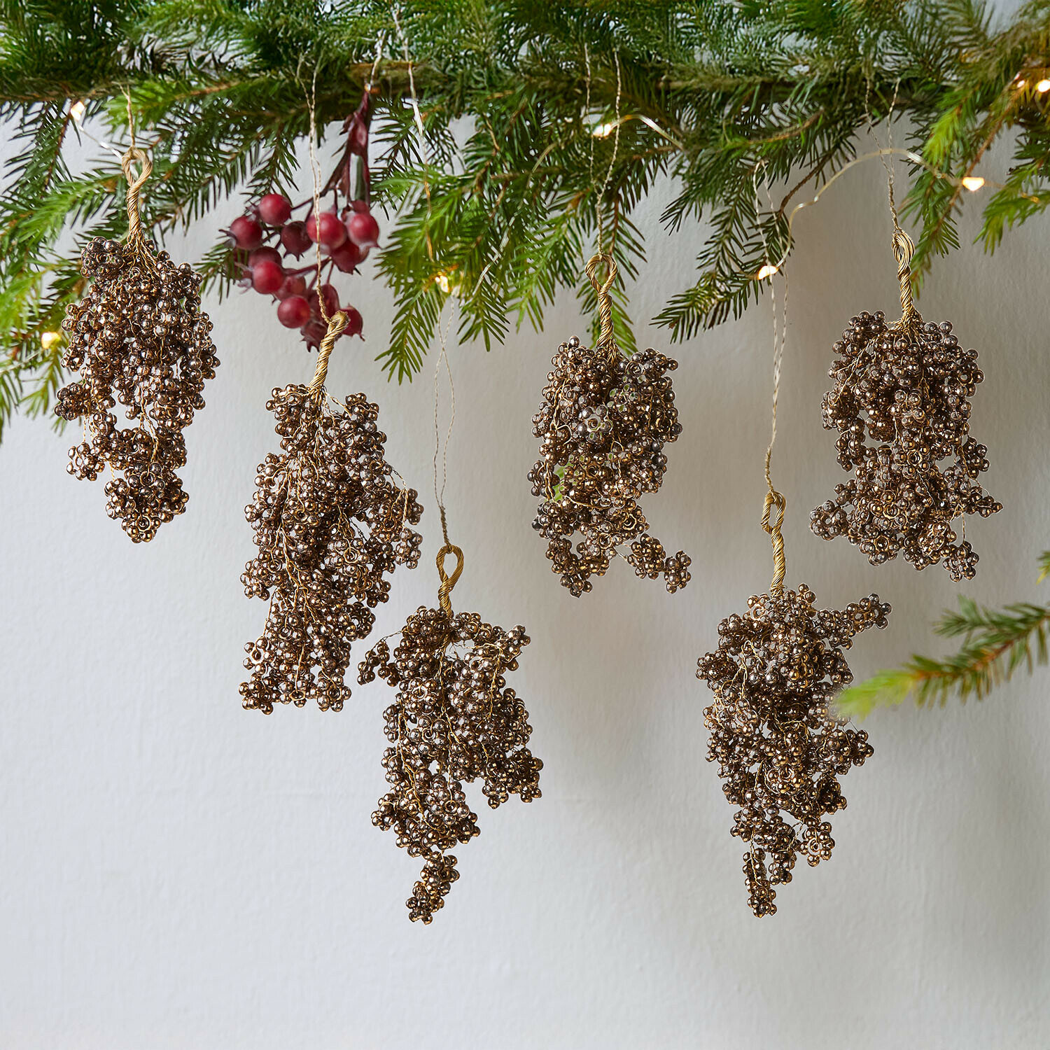 Gouden kralenversieringen hangend aan dennentakken, feestelijke kerstdecoratie