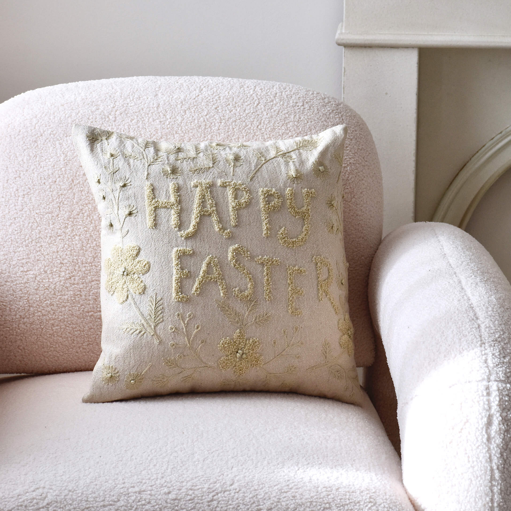 Beige sierkussen met Happy Easter borduurwerk op lichte stoel in pasteltinten