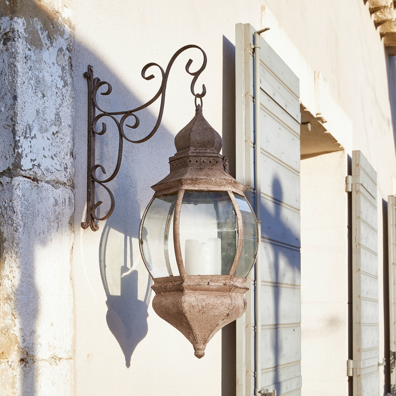 Rustieke metalen wandlantaarn in roestkleur met helder glas en witte kaars voor buiten
