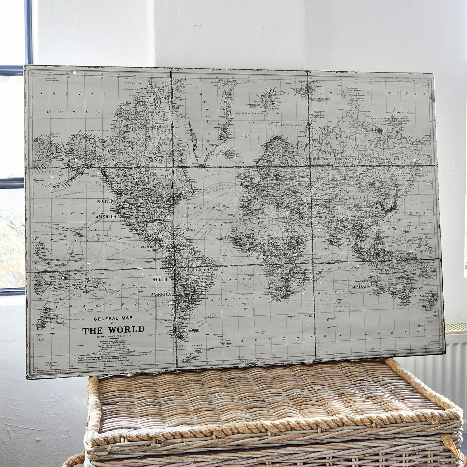 Afbeelding Macolin Vintage wereldkaart in grijstinten op een rieten mand als interieurdecoratie