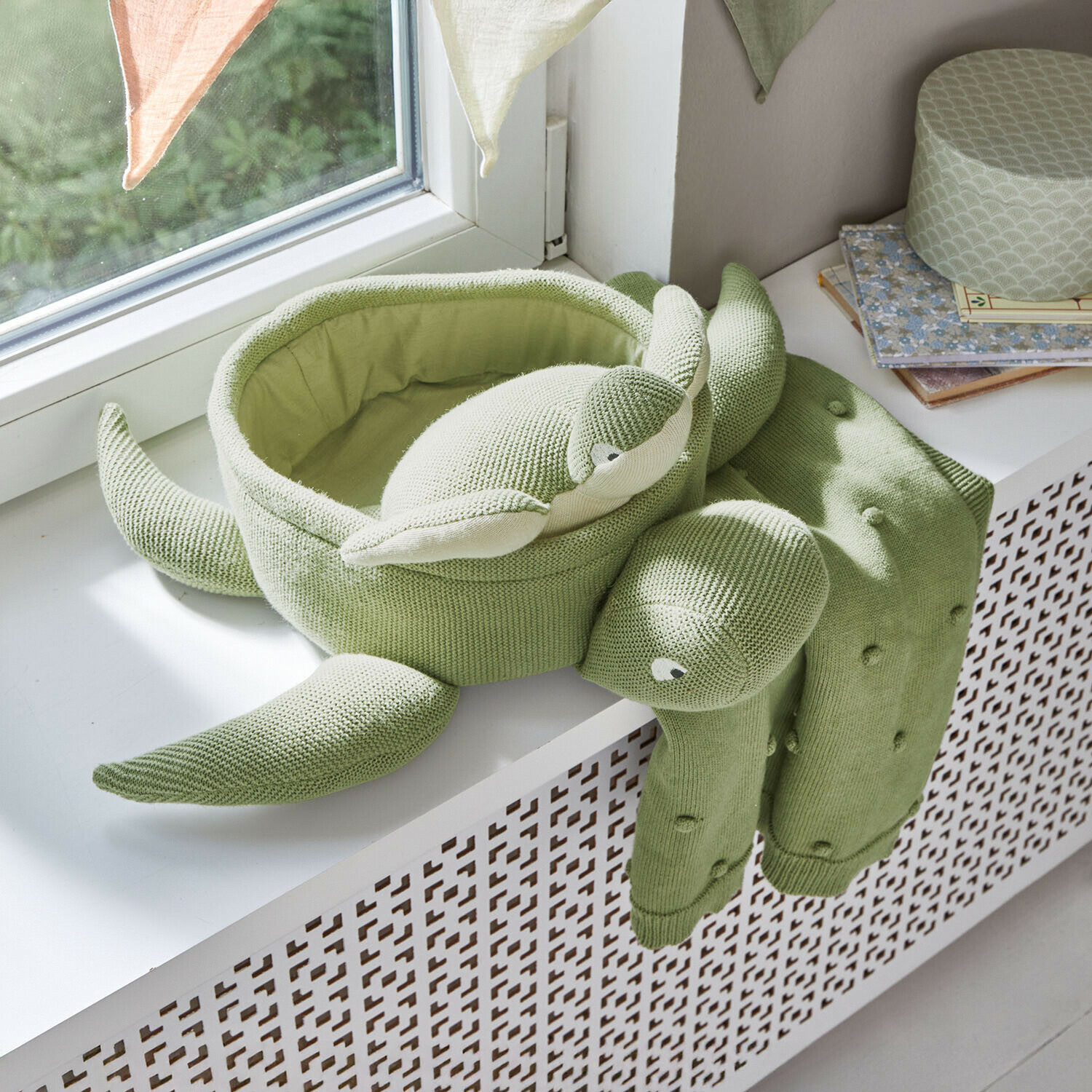 Zachte groene gebreide schildpadkussen op vensterbank, decoratie voor kinderkamer