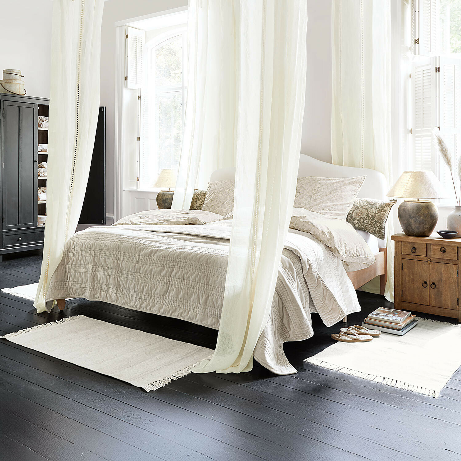 Gezellige slaapkamer met licht beddengoed en houten nachtkastje op donkere vloer