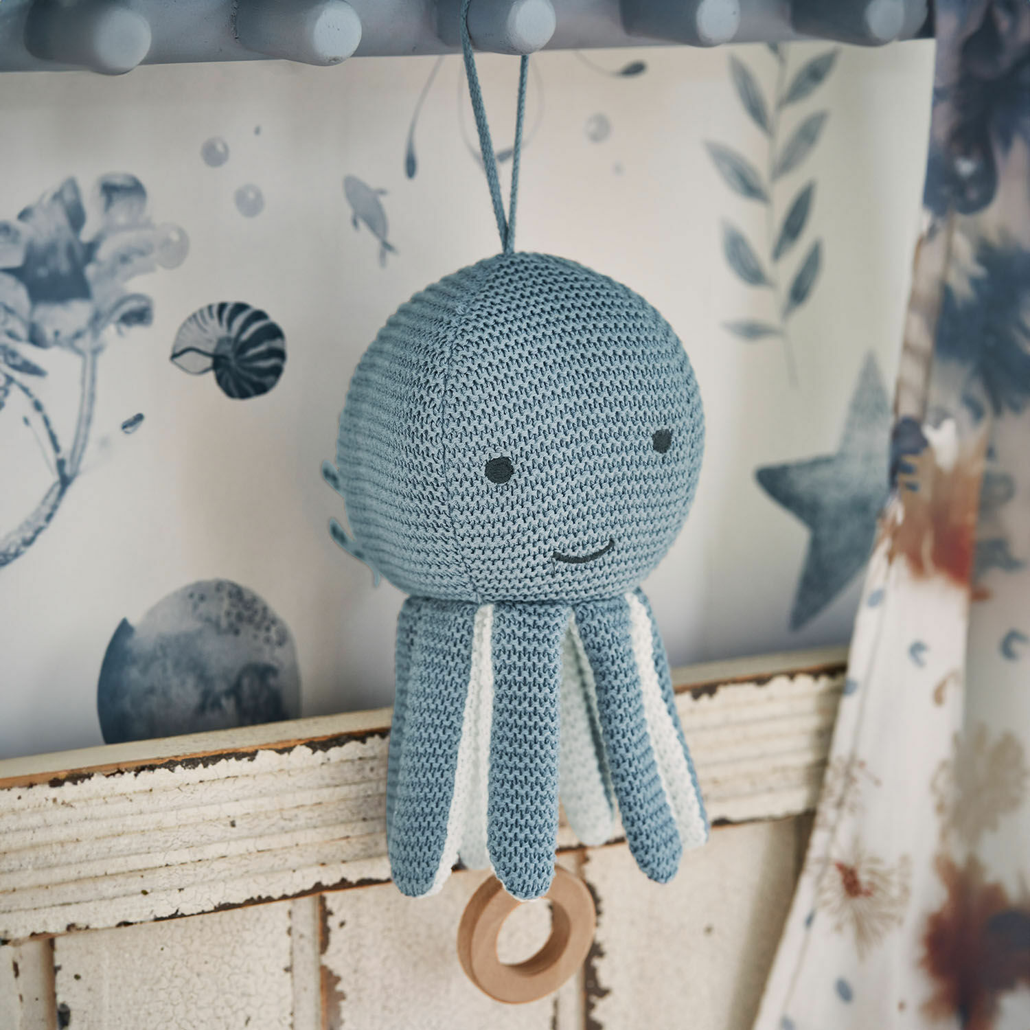 Muziekknuffel Cozycot Gebreide blauwe octopus met witte details en houten ring om op te hangen, zachte kinderdecoratie