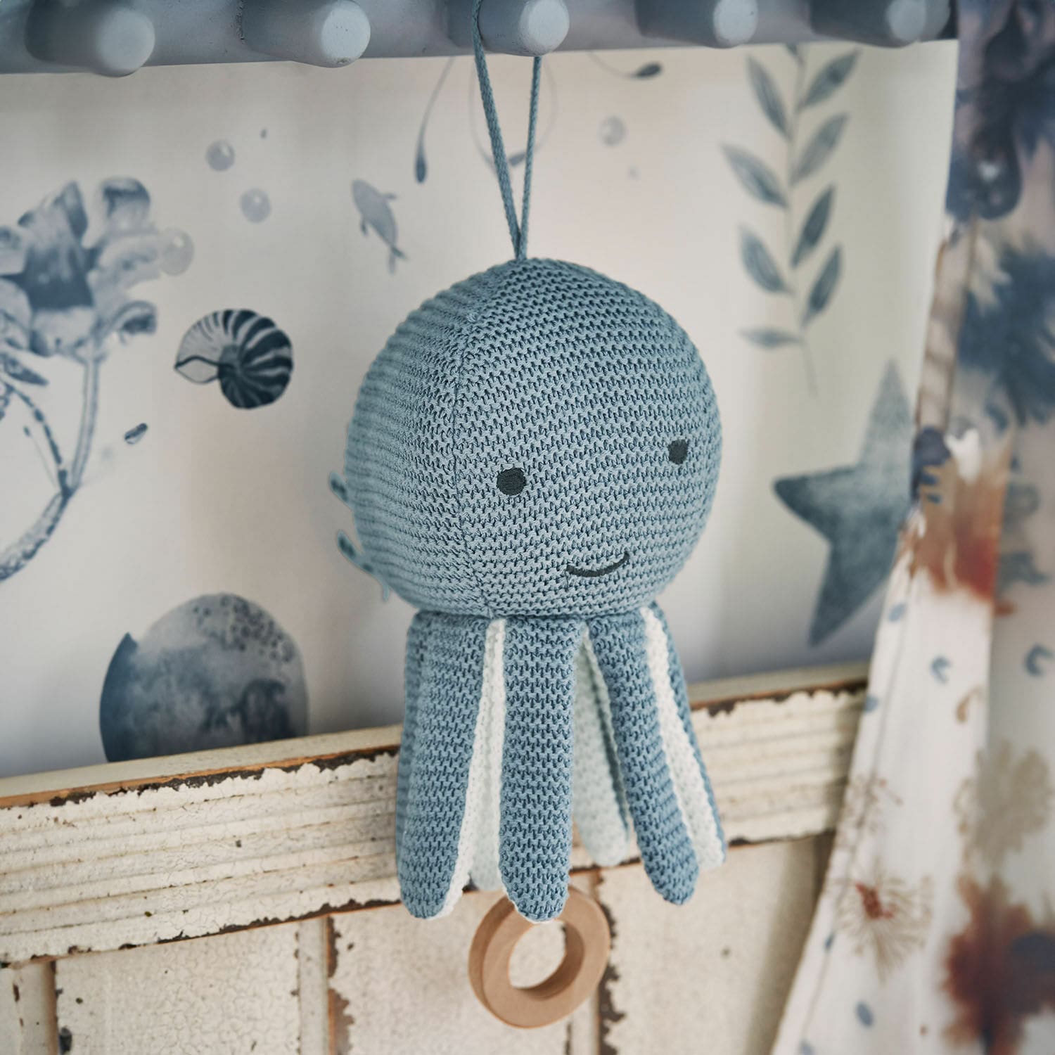 Muziekknuffel Cozycot Gebreide blauwe octopus met witte details en houten ring om op te hangen, zachte kinderdecoratie