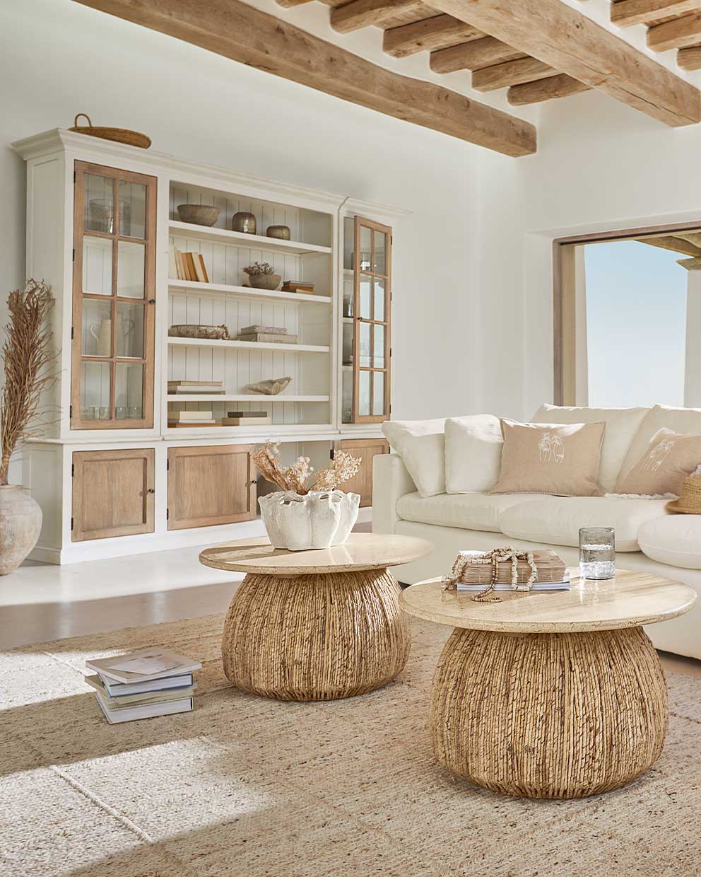 Twee ronde salontafels van natuurlijk hout en riet in lichte woonkamer met witte bank