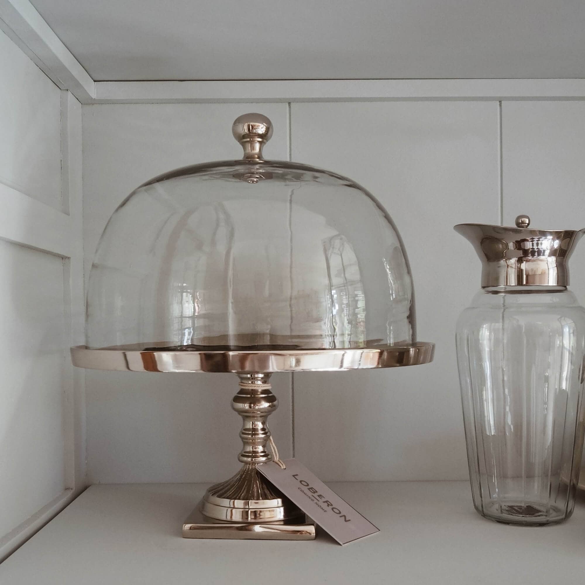 Glazen stolp op gouden metalen standaard voor het serveren van taarten en desserts in slow living stijl
