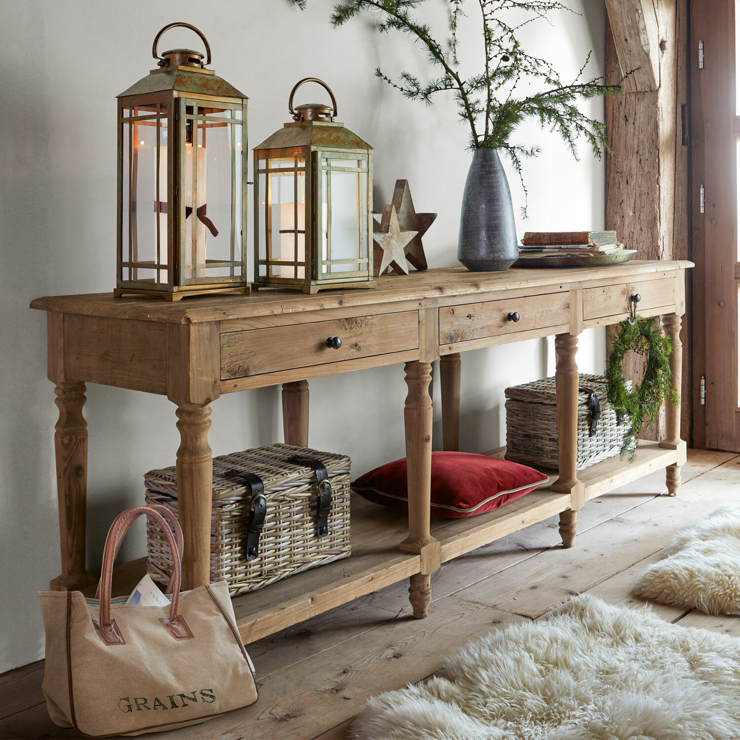 Sidetable Misérieux Houten sidetable met drie lades, decoratieve lantaarns en rieten manden in een gezellige ruimte