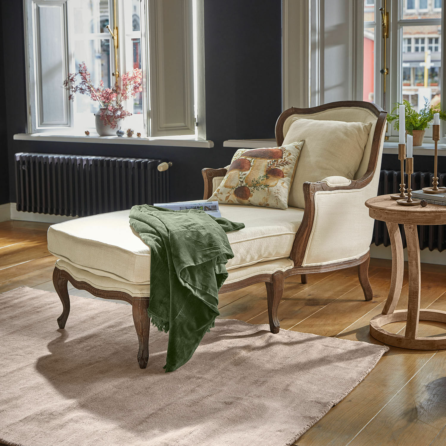 Chaise longue Muel Beige ligstoel met houten frame en groene deken in lichte woonkamer met houten vloer