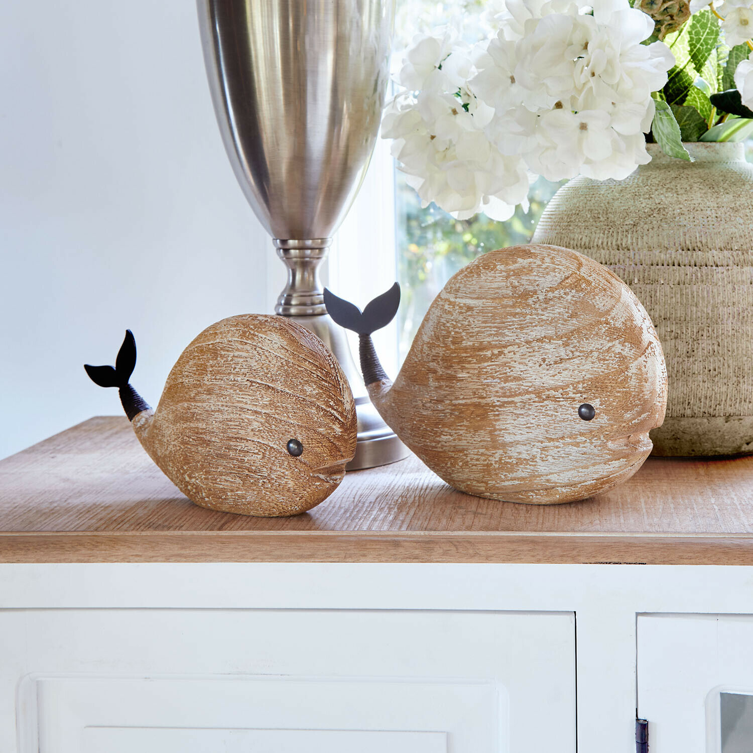 Houten walvisdecoraties in natuurlijke kleur met zwarte staart op lichte tafel in woonkamer