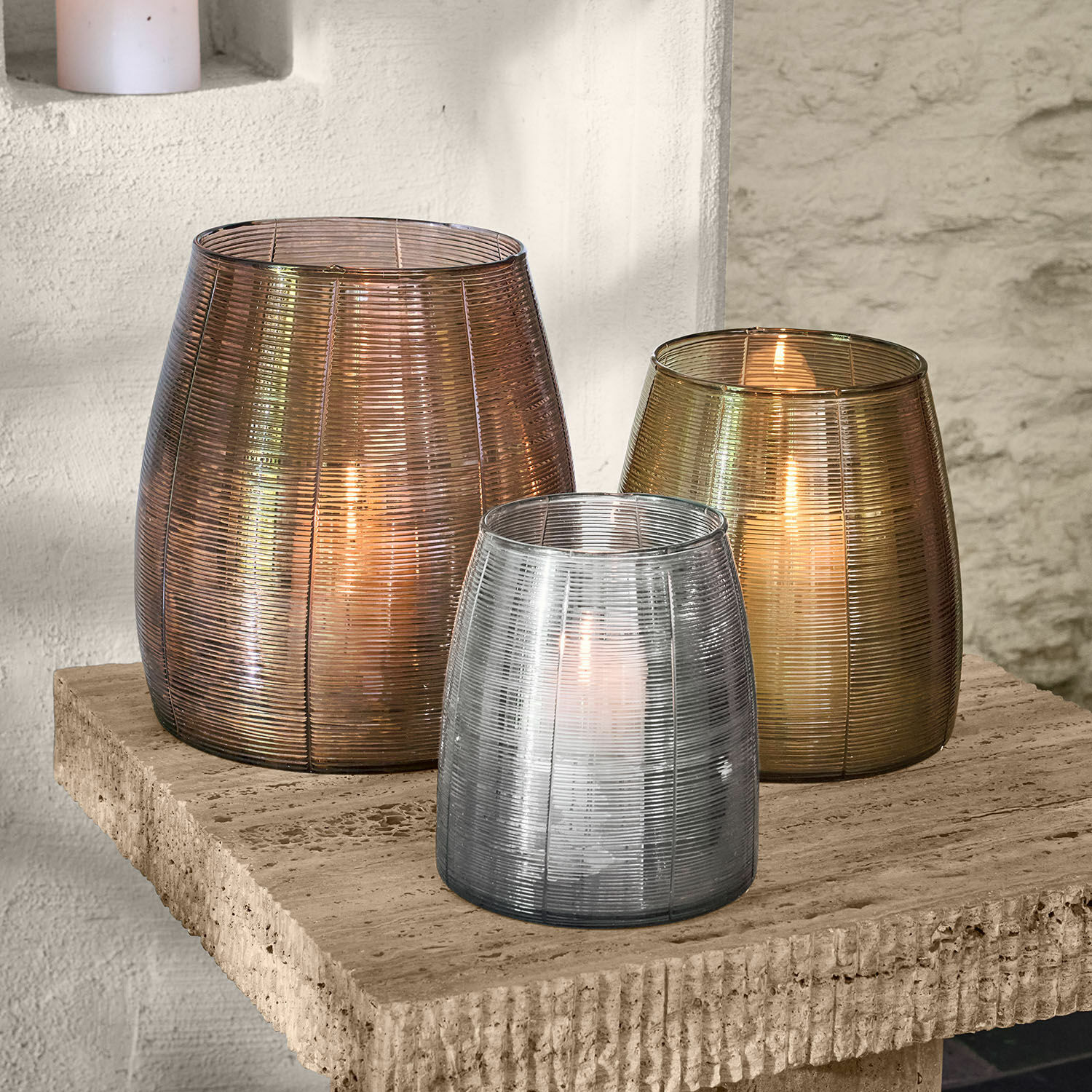 Set van drie glazen lantaarns in brons, goud en zilver op een stenen blad