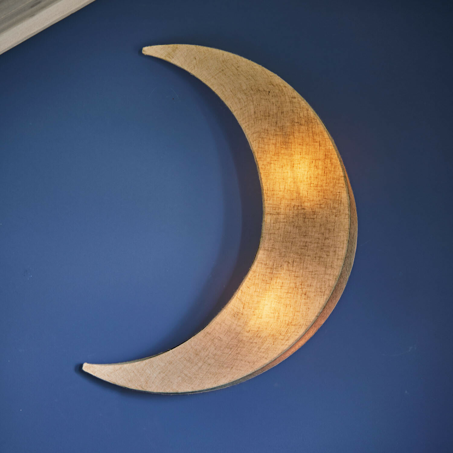 Wandlamp Jollymoon Wandlamp in maanvorm van beige stof tegen een blauwe muur