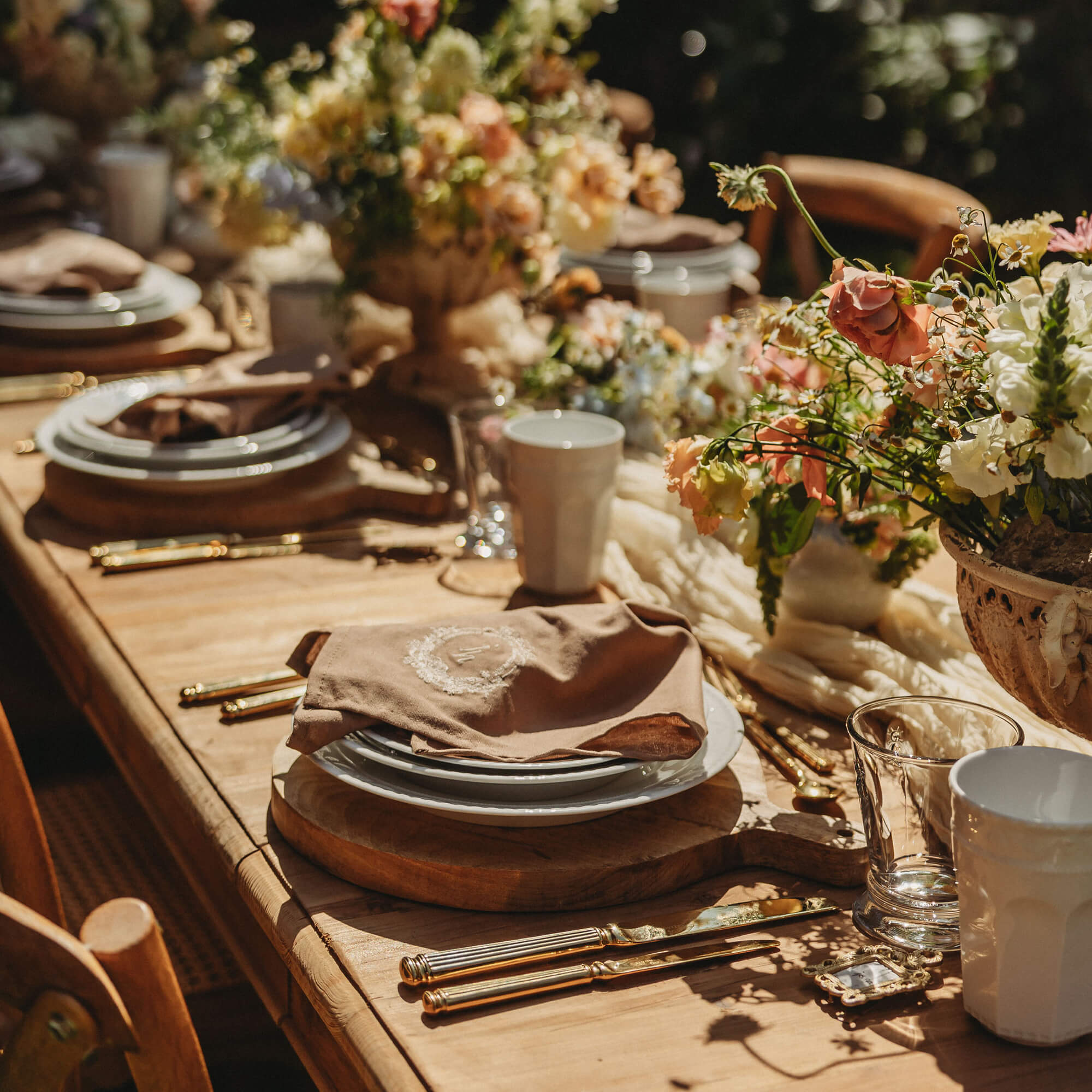 Rustieke houten tafel met servies, gouden bestek en bloemstuk voor feestelijke gelegenheid
