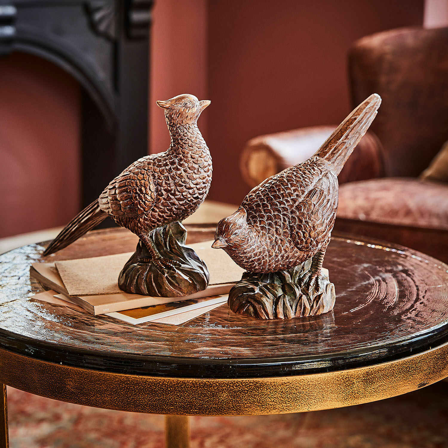 Decoratief vogeltje set van 2 Vivoso Twee bruine houten vogelbeelden op een glazen tafel in een gezellige woonkamer