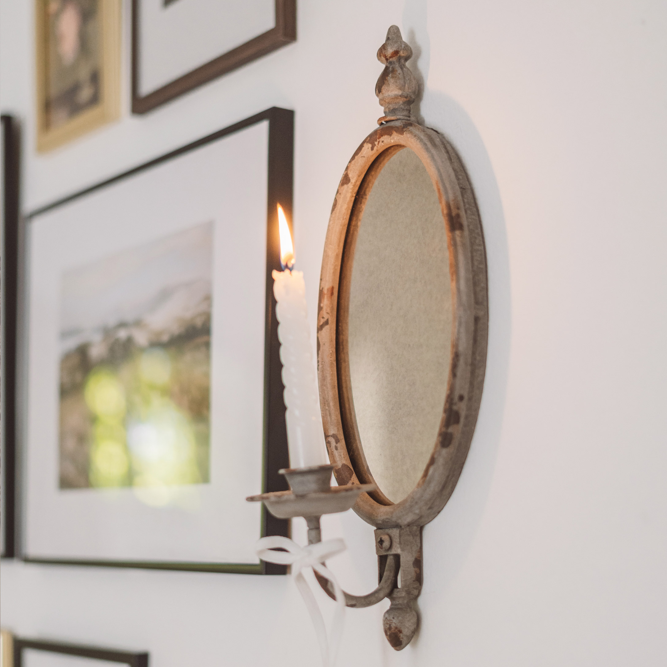 Rustieke metalen wandkandelaar met ovale spiegel en witte kaars in vintage stijl