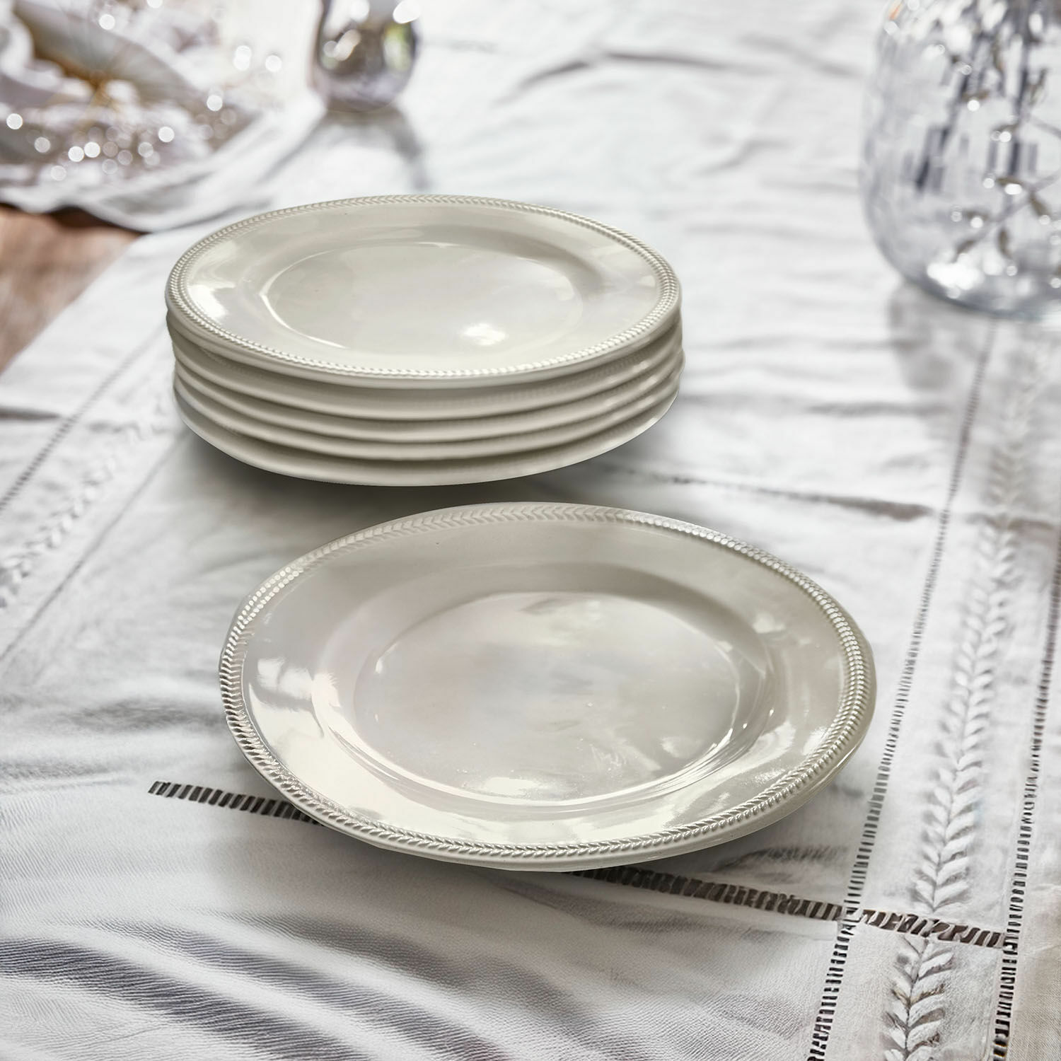 Set witte keramische borden met decoratieve rand op een linnen tafelkleed voor de eetkamer