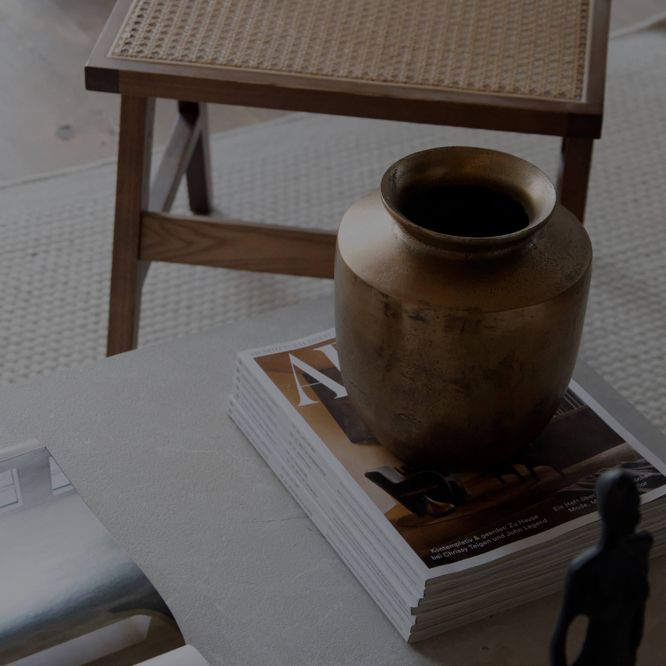 Decoratieve messing vaas op stapel tijdschriften op grijze tafel in modern interieur