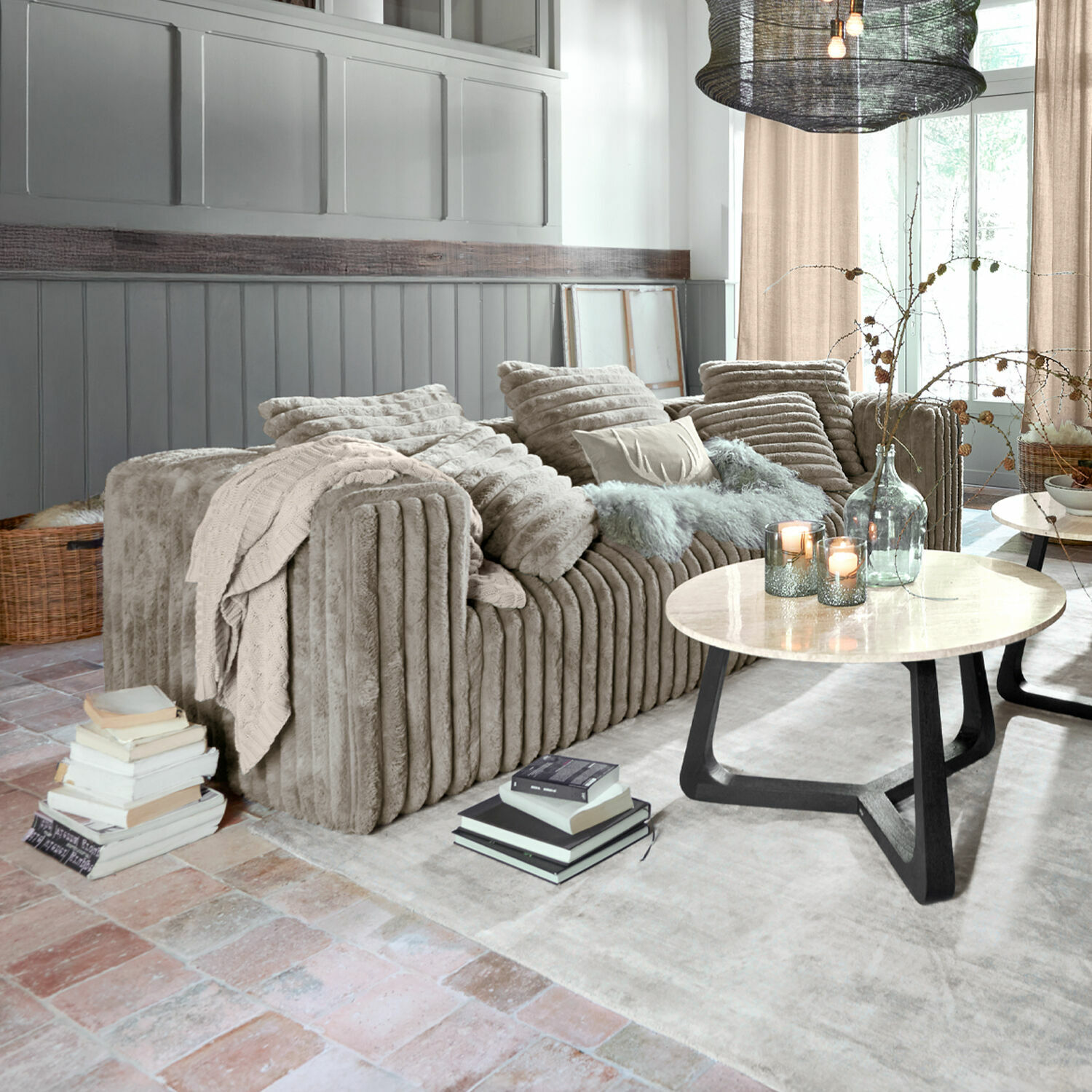 Bank Roucemont Beige pluche bank met kussens en deken in moderne woonkamer met marmeren salontafel