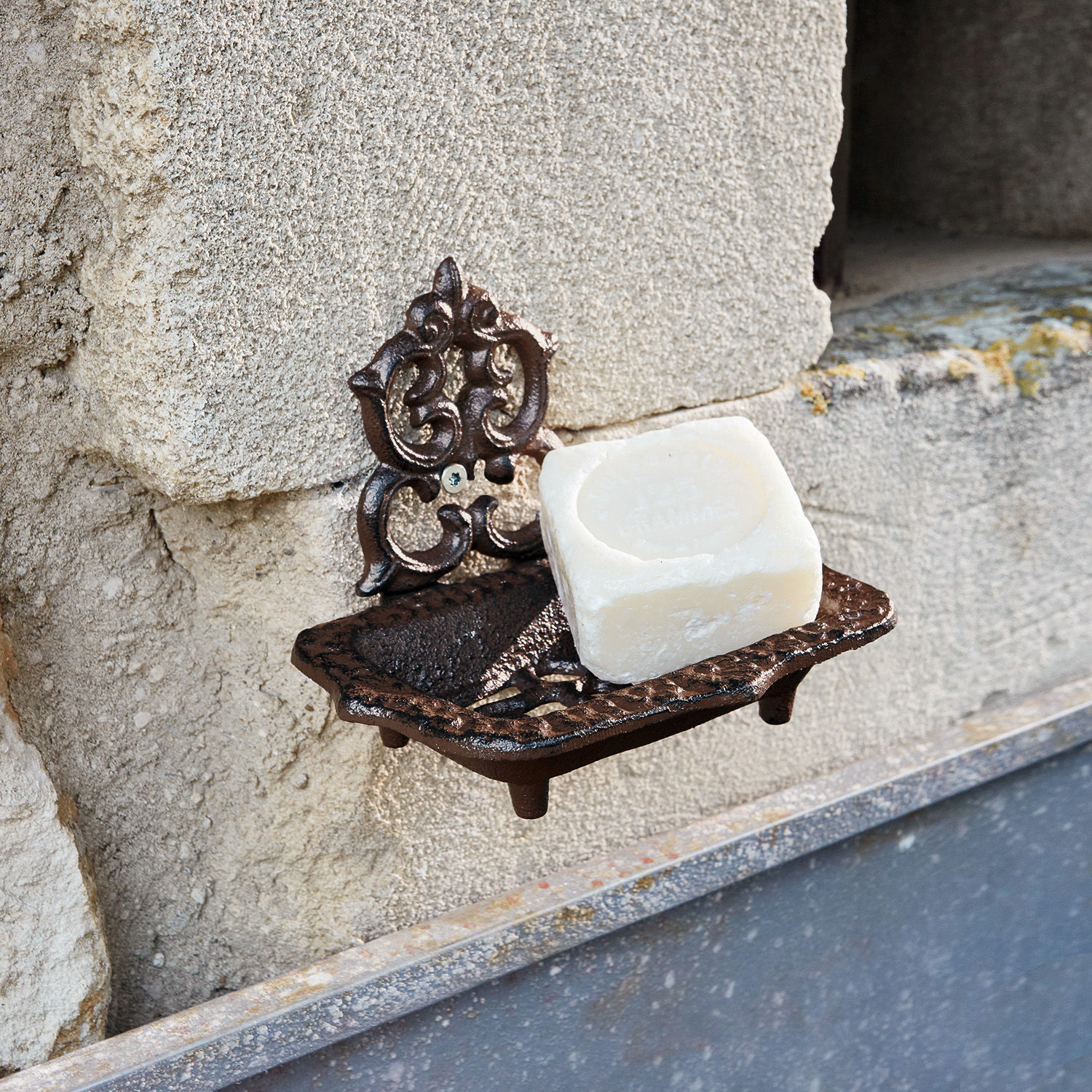 Bruine gietijzeren wandzeepbak met witte zeep aan stenen muur bevestigd