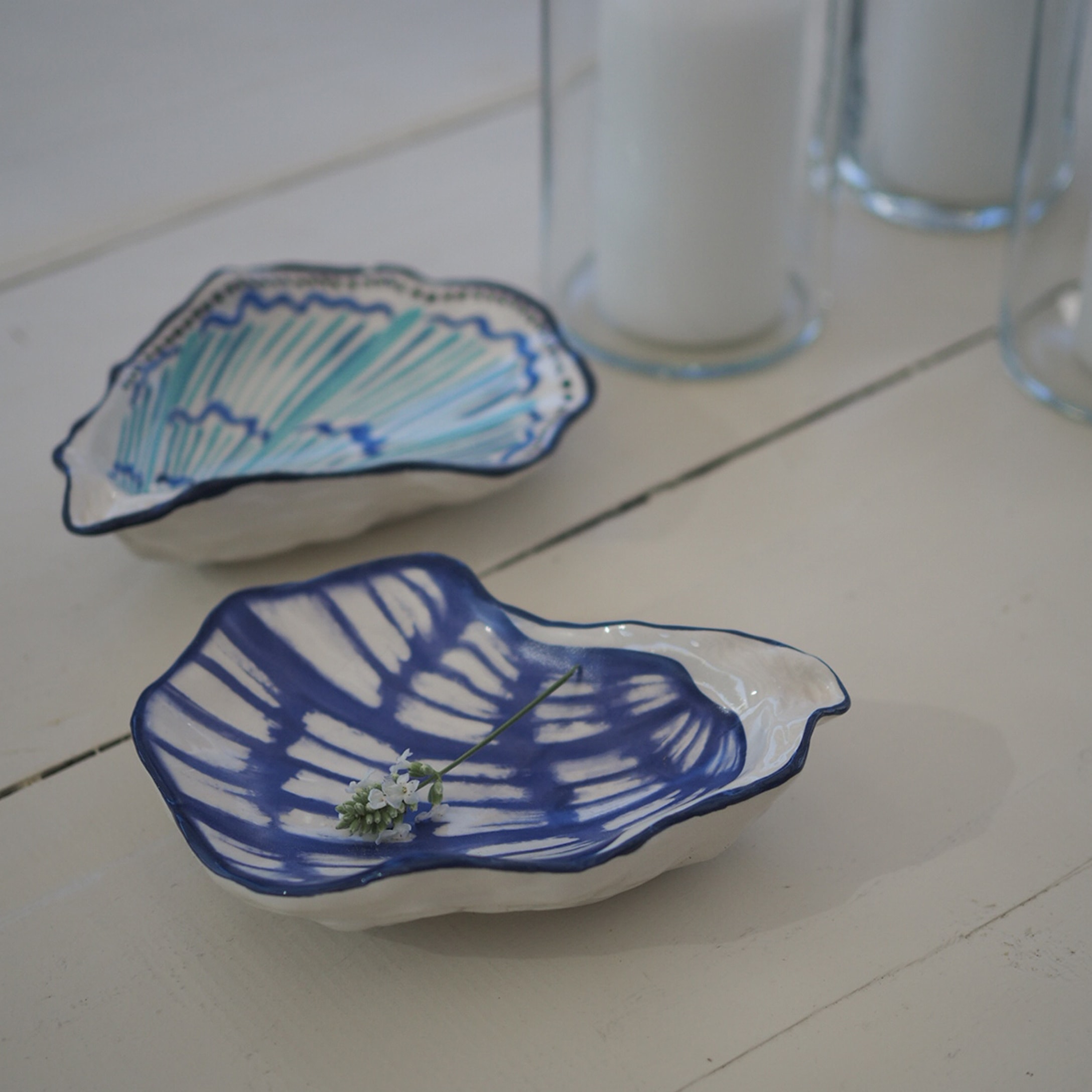 Keramische schaaltjes in schelpvorm met blauw en turquoise patroon op witte achtergrond, tafeldecoratie