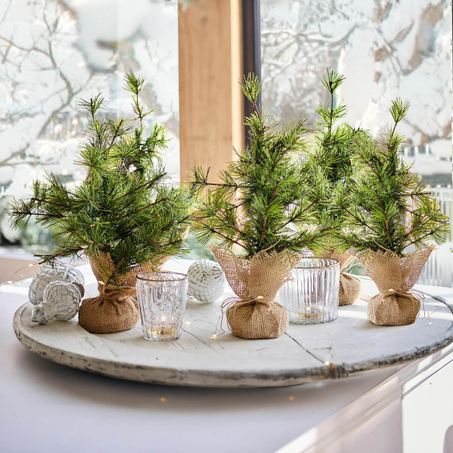 Sierboom set van 4 Millies Kleine decoratieve kerstboompjes in jute zakjes op een wit dienblad met kaarsen en kerstversiering
