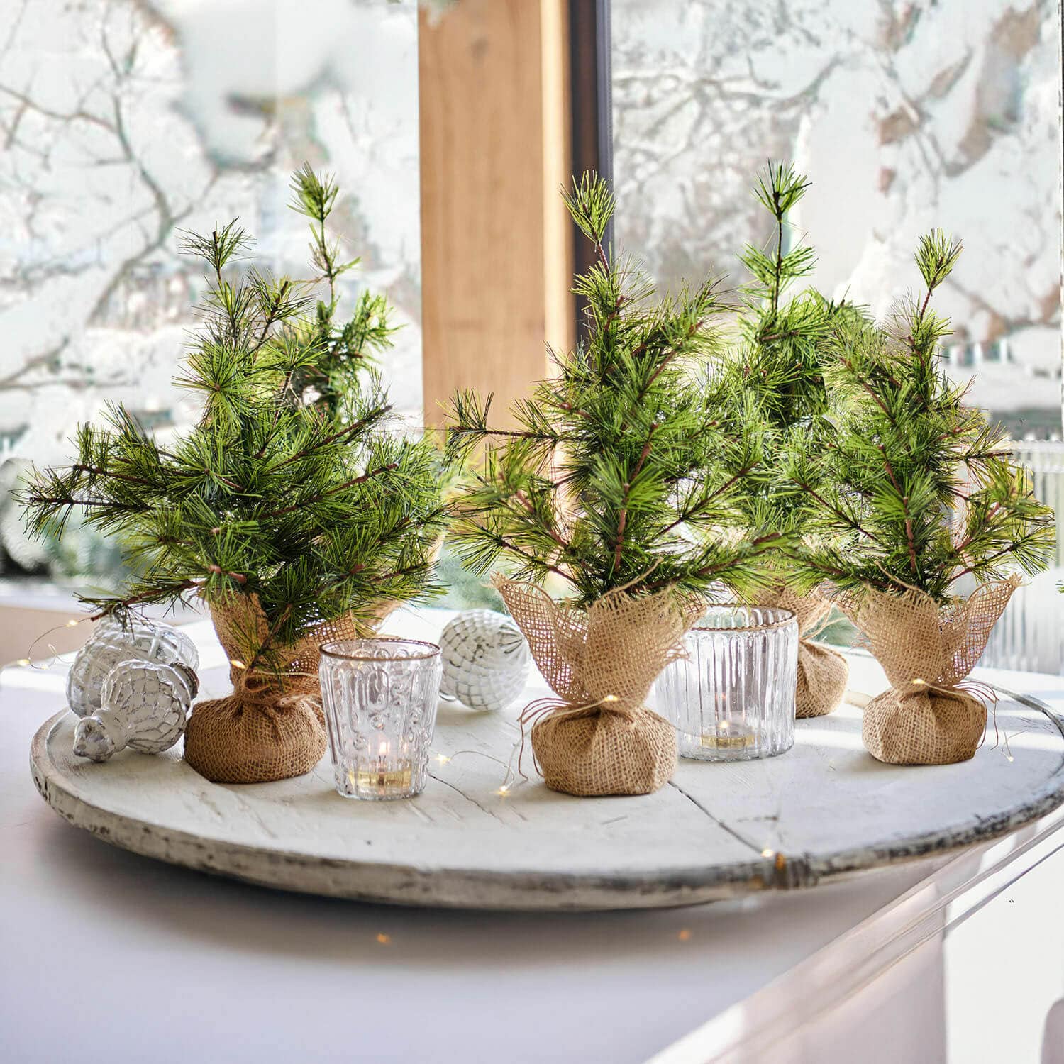 Sierboom set van 4 Millies Kleine decoratieve kerstboompjes in jute zakjes op een wit dienblad met kaarsen en kerstversiering