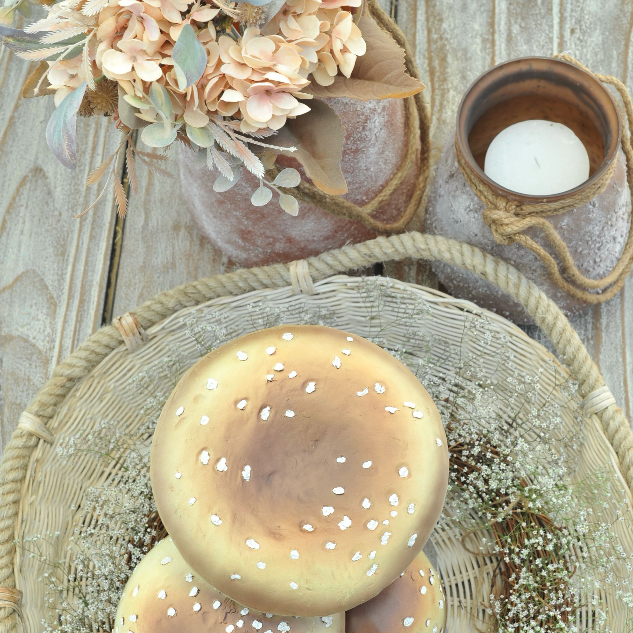 Decoratieve herfstpaddenstoelen in rieten mand met gedroogde bloemen op houten tafel