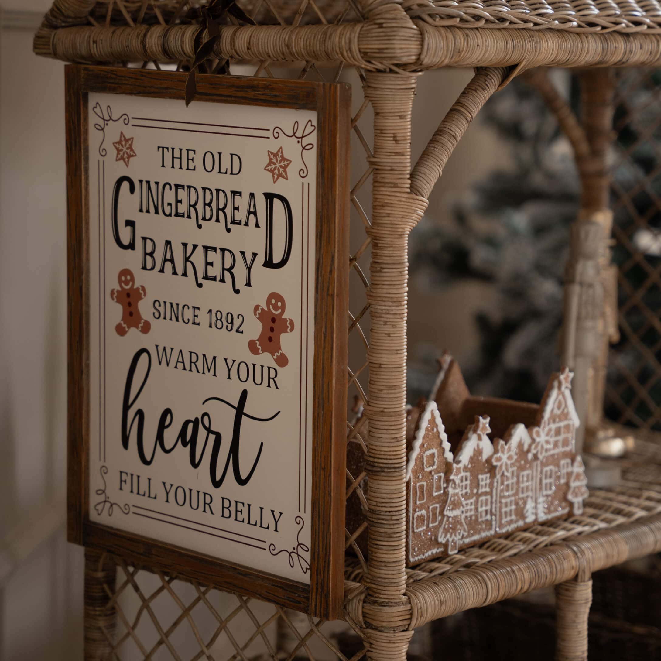 Houten bord met tekst over peperkoekbakkerij op rotan plank met peperkoek dorp decoratie