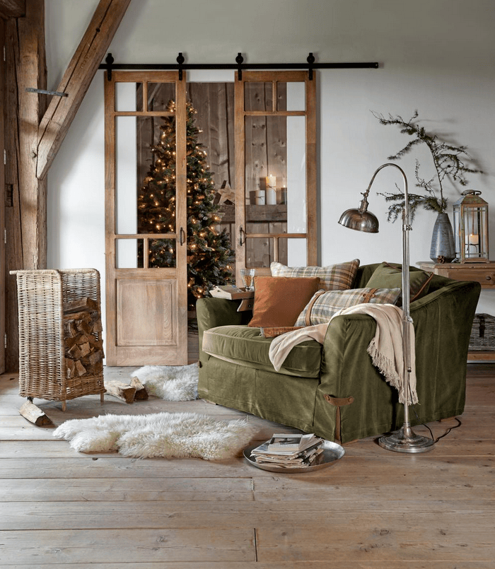 Groene stoffen fauteuil in rustieke woonkamer met houten vloer en kerstdecoratie
