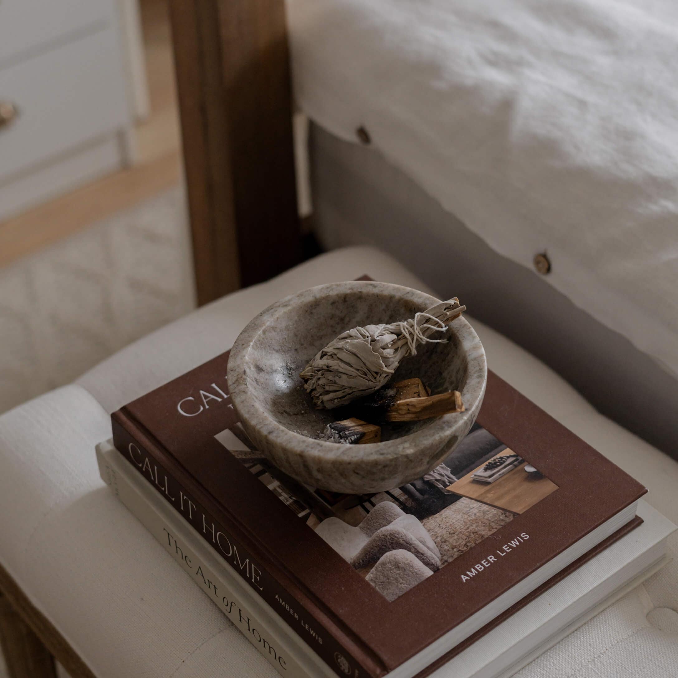 Grijs stenen kom met gedroogde kruiden op een stapel woonboeken