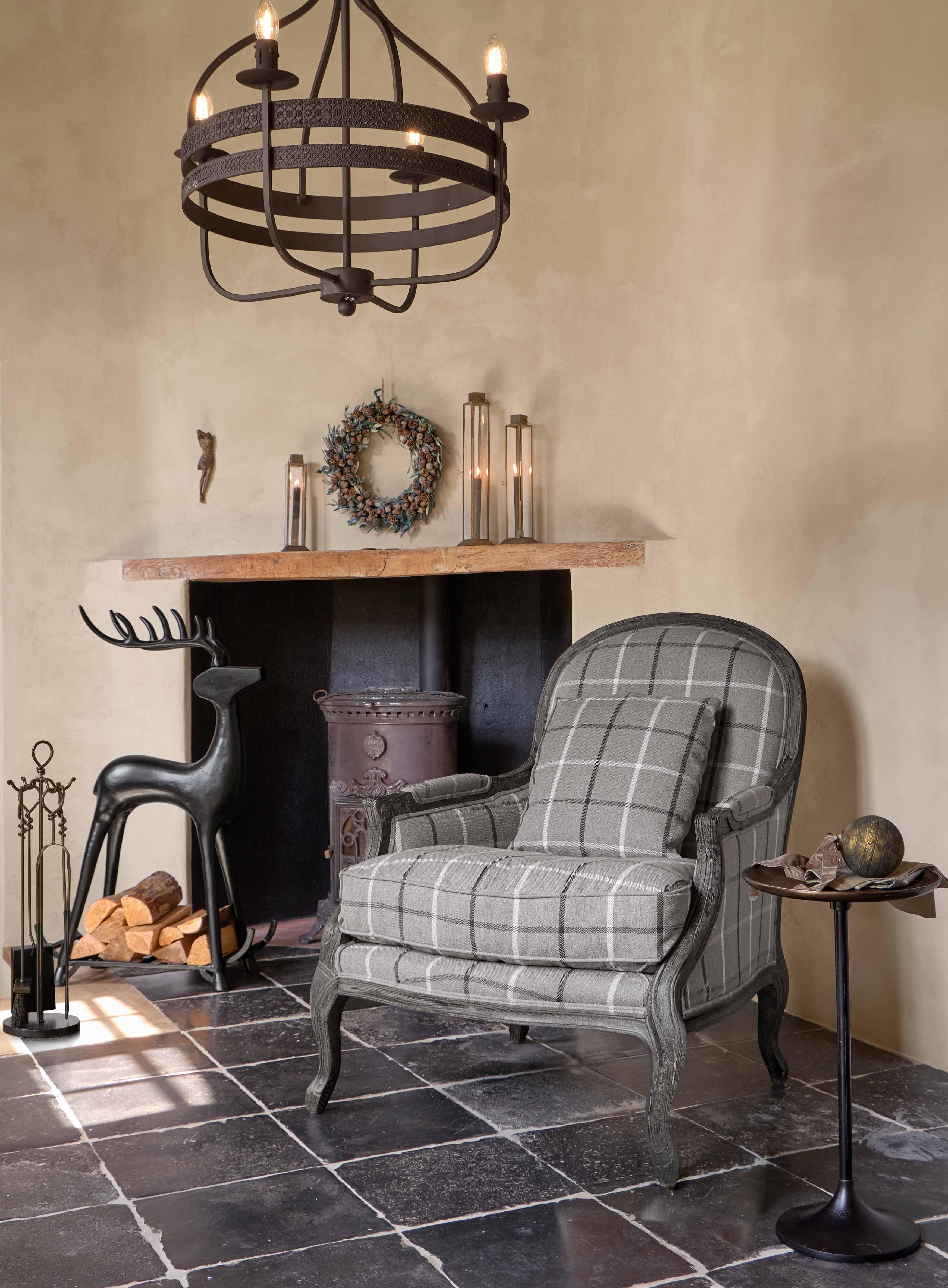 Grijze geruite fauteuil met houten frame in klassieke stijl in een gezellige woonkamer met open haard
