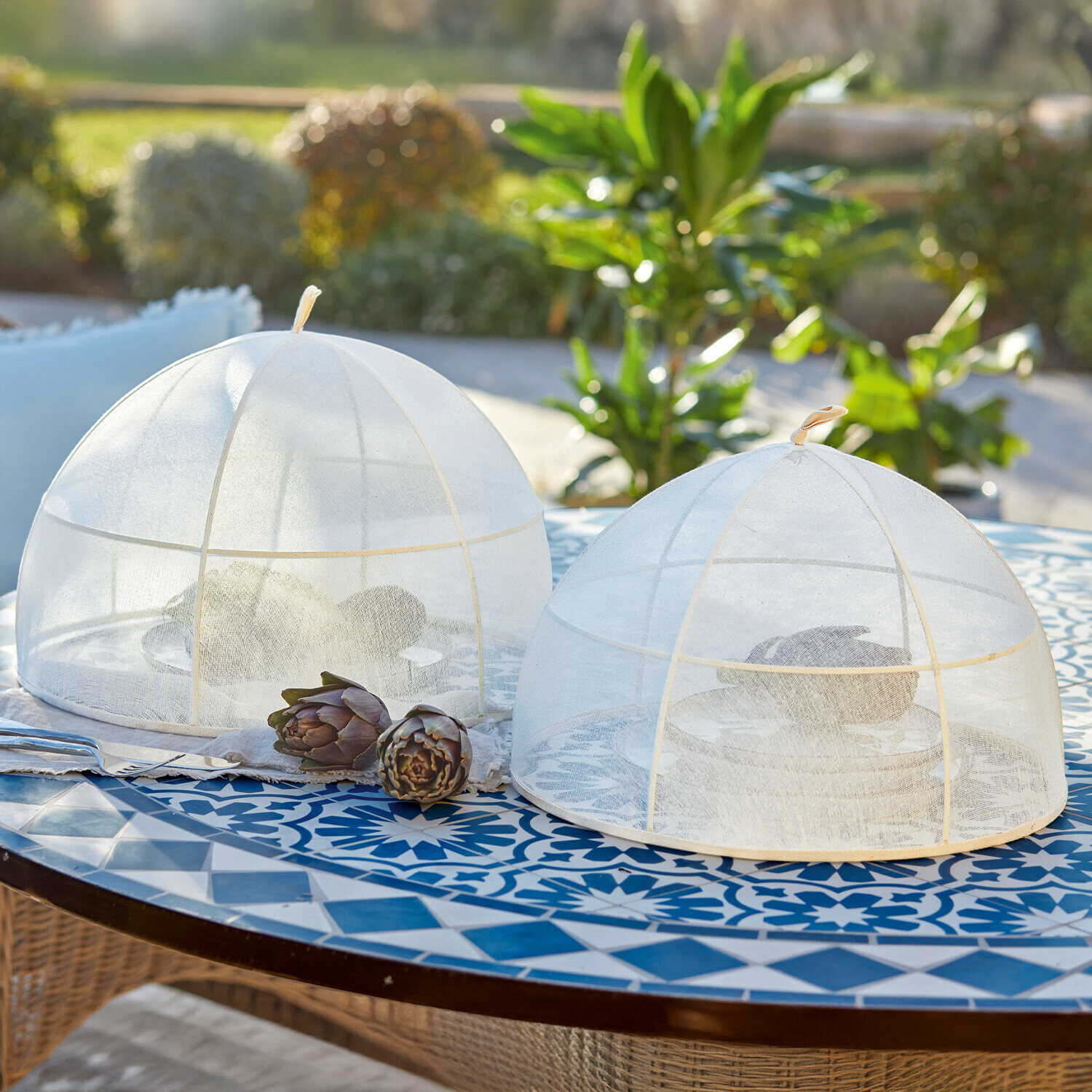 Twee witte gaas voedselkappen op een blauw patroon tafelblad, bescherming tegen insecten buiten