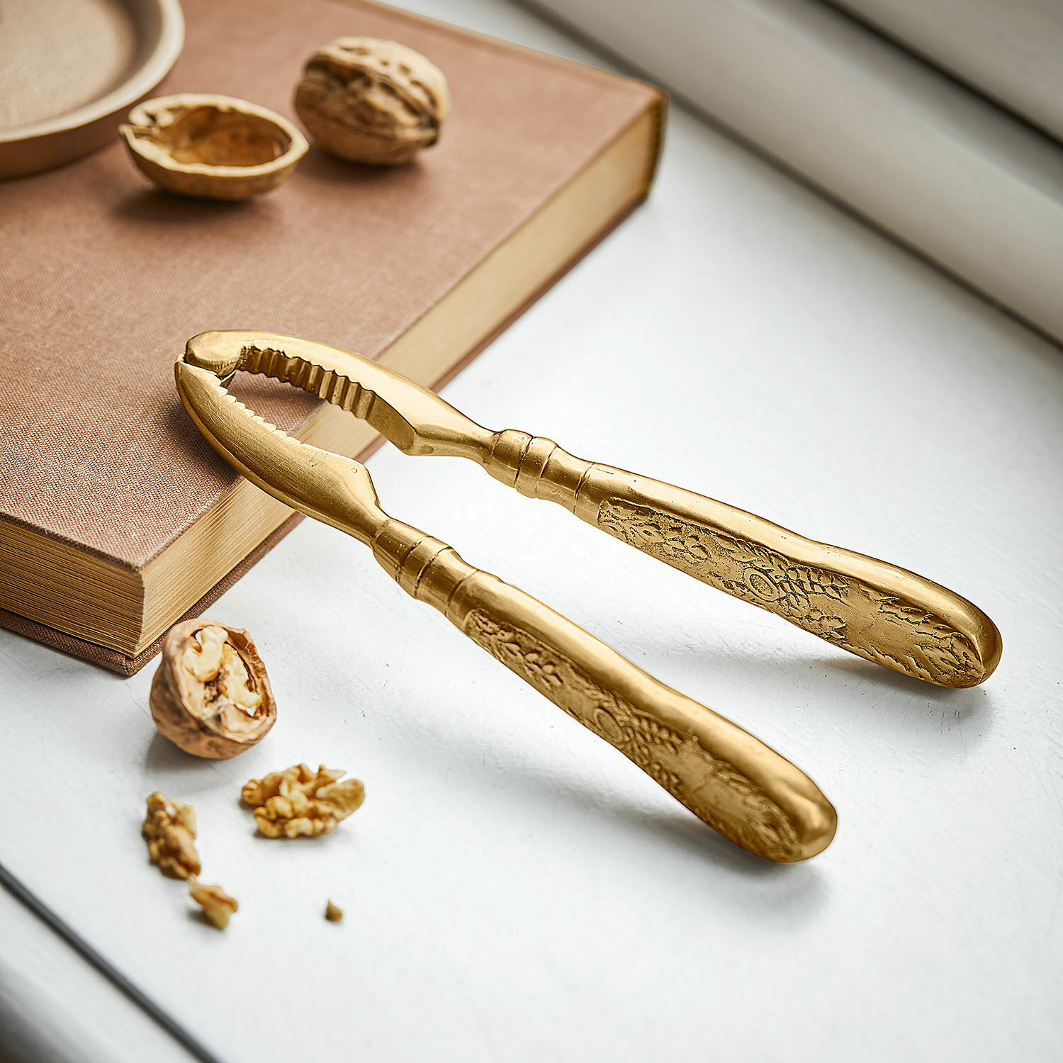 Notenkraker Solenna Gouden metalen notenkraker met decoratief patroon op de handvatten op witte achtergrond